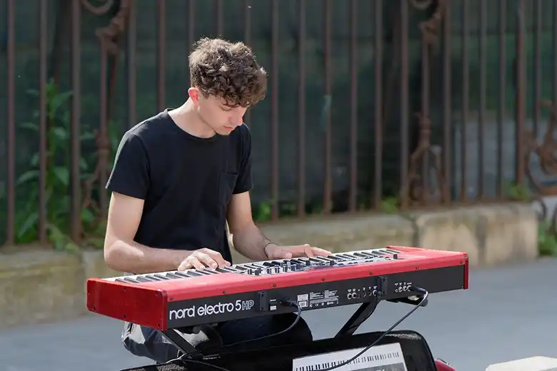 Joven tocando un teclado en una banqueta