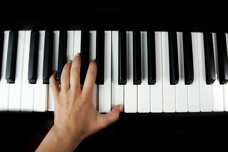 Mano izquierda tocando un acorde en piano