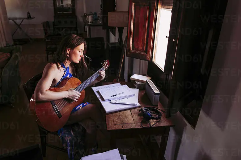 Mujer leyendo partitura mientras toca guitarra