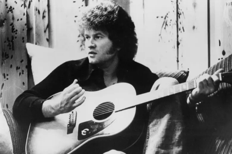 Es una imagen blanco y negro de Terry Jacks con su guitarra acústica