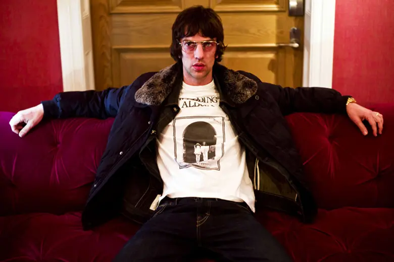 La imagen muestra a Richard Ashcroft sentado en un sofá con los brazos extendidos