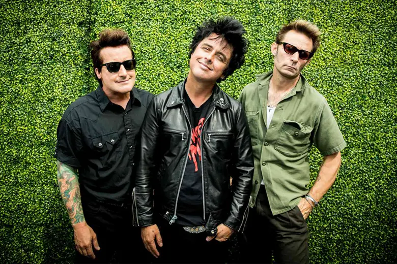 La imagen muestra a los 3 miembros de la banda Green Day sonrientes