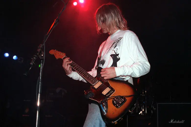 La imagen muestra a Kurt Cobain de Nirvana tocando una guitarra Jazzmaster en el escenario