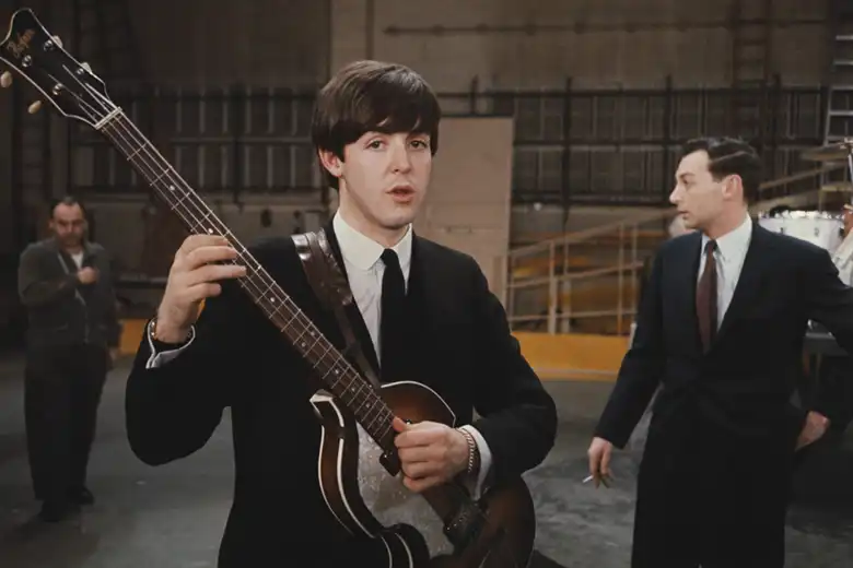 La imagen muestra a Paul McCartney tocando su bajo Höfner mientras ve hacía la cámara.