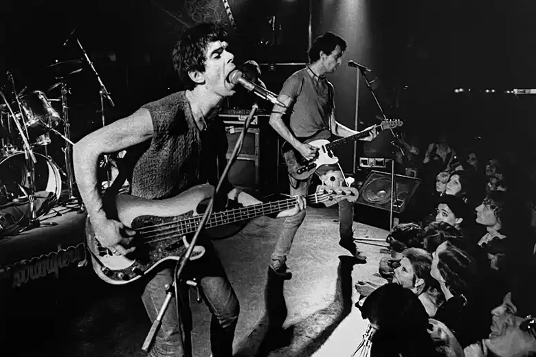 Es una imagen en blanco y negro que muestra a The Stranglers tocando en el escenario.